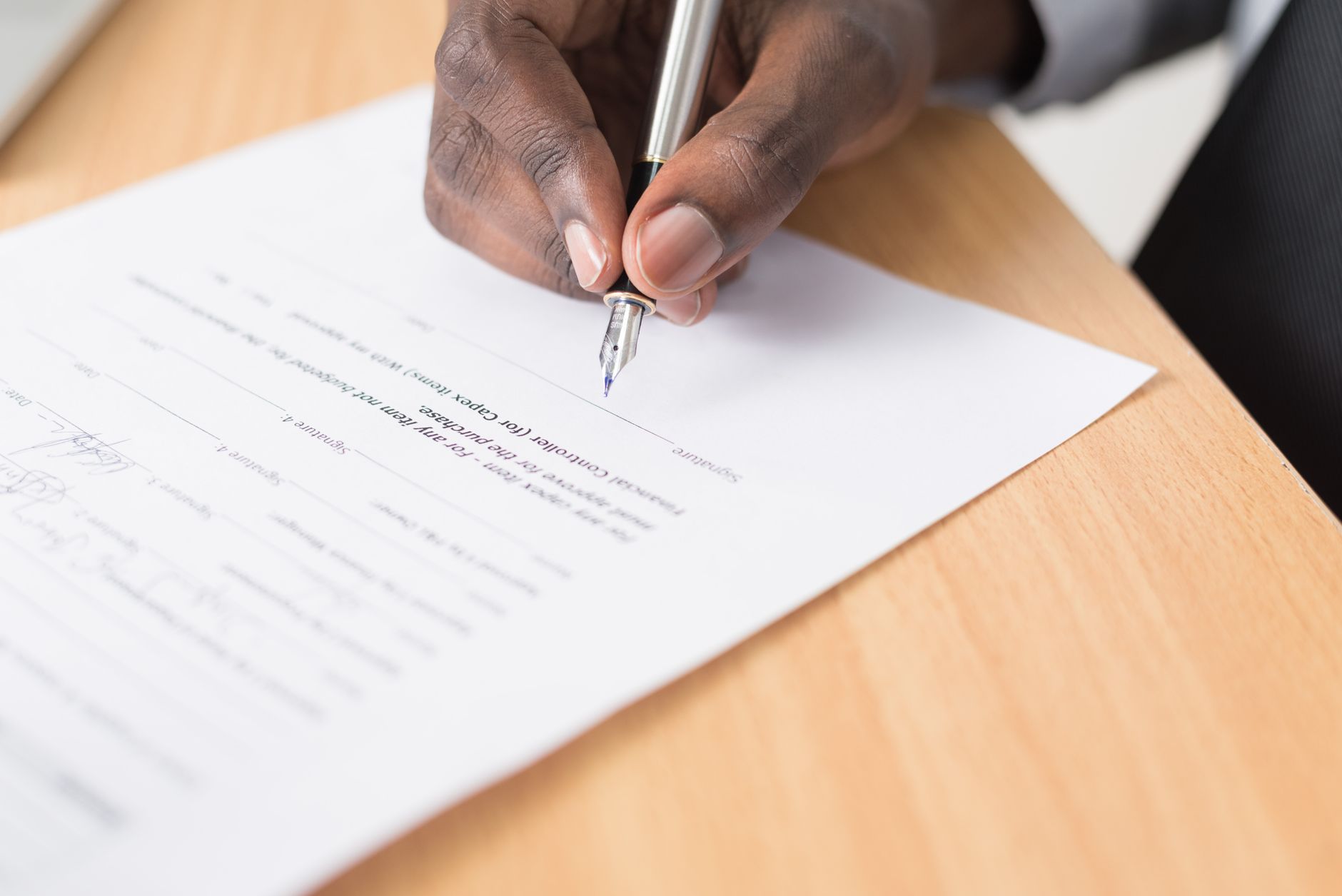 Mão assinando um documento em close